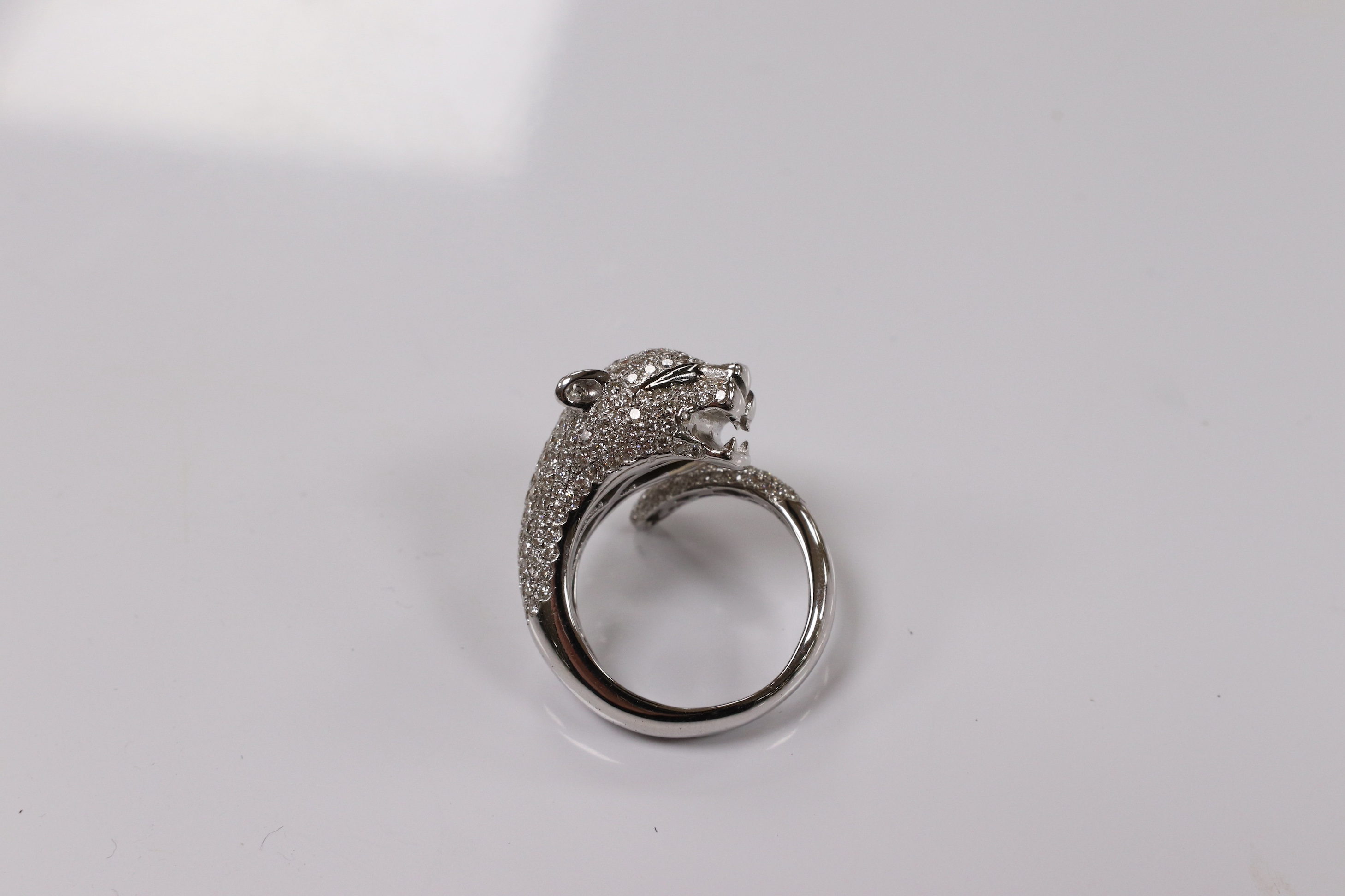 A modern Cartier style 18k white metal and pave set diamond chip dress ring, modelled as the head and tail of a leopard, size M, gross 9 grams. Condition - good